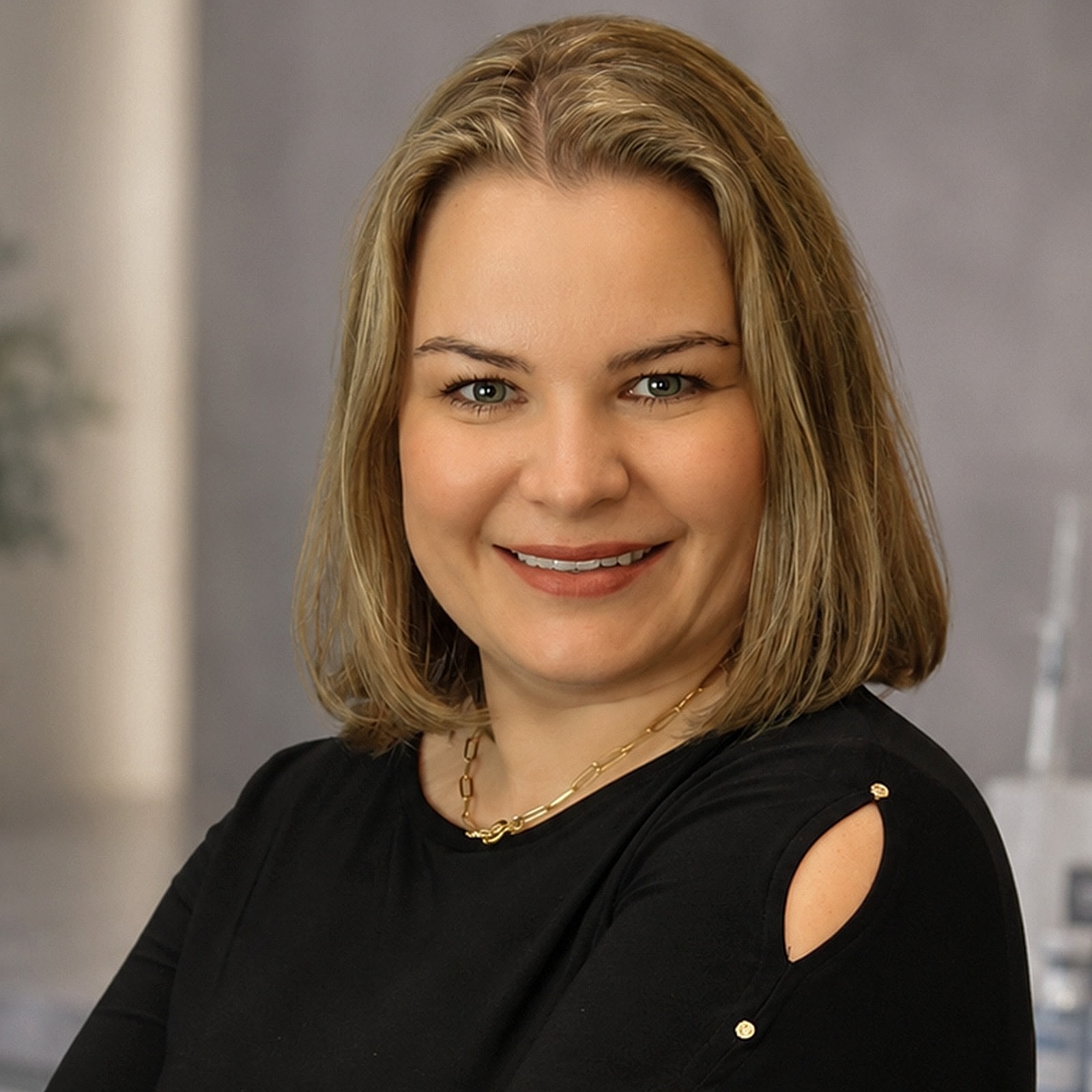 Smiling woman in black shirt with arms crossed.