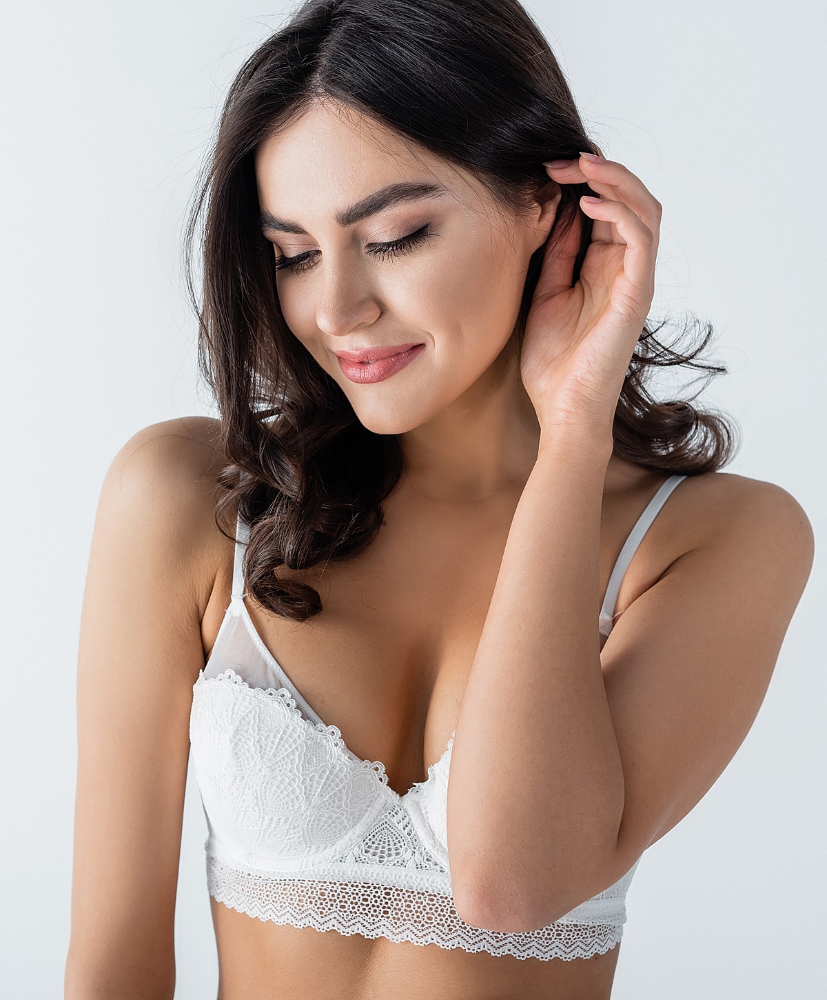 Model in white lingerie smiling softly.