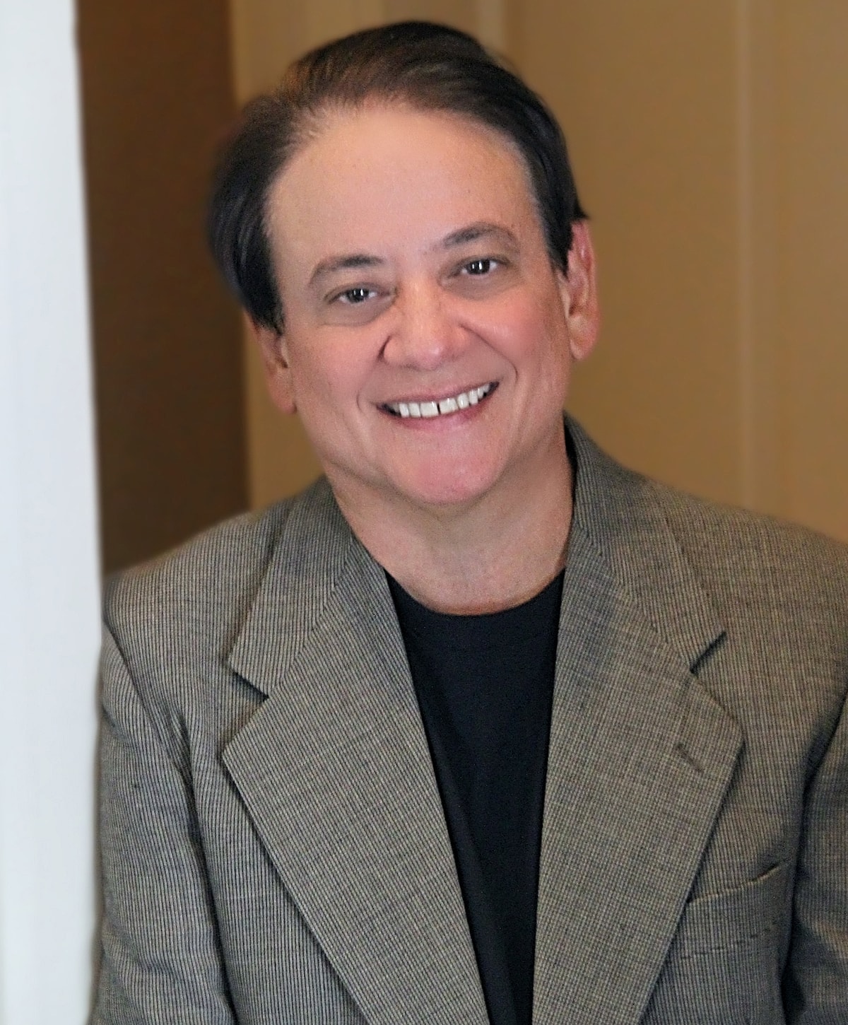 Smiling man in a gray blazer portrait.