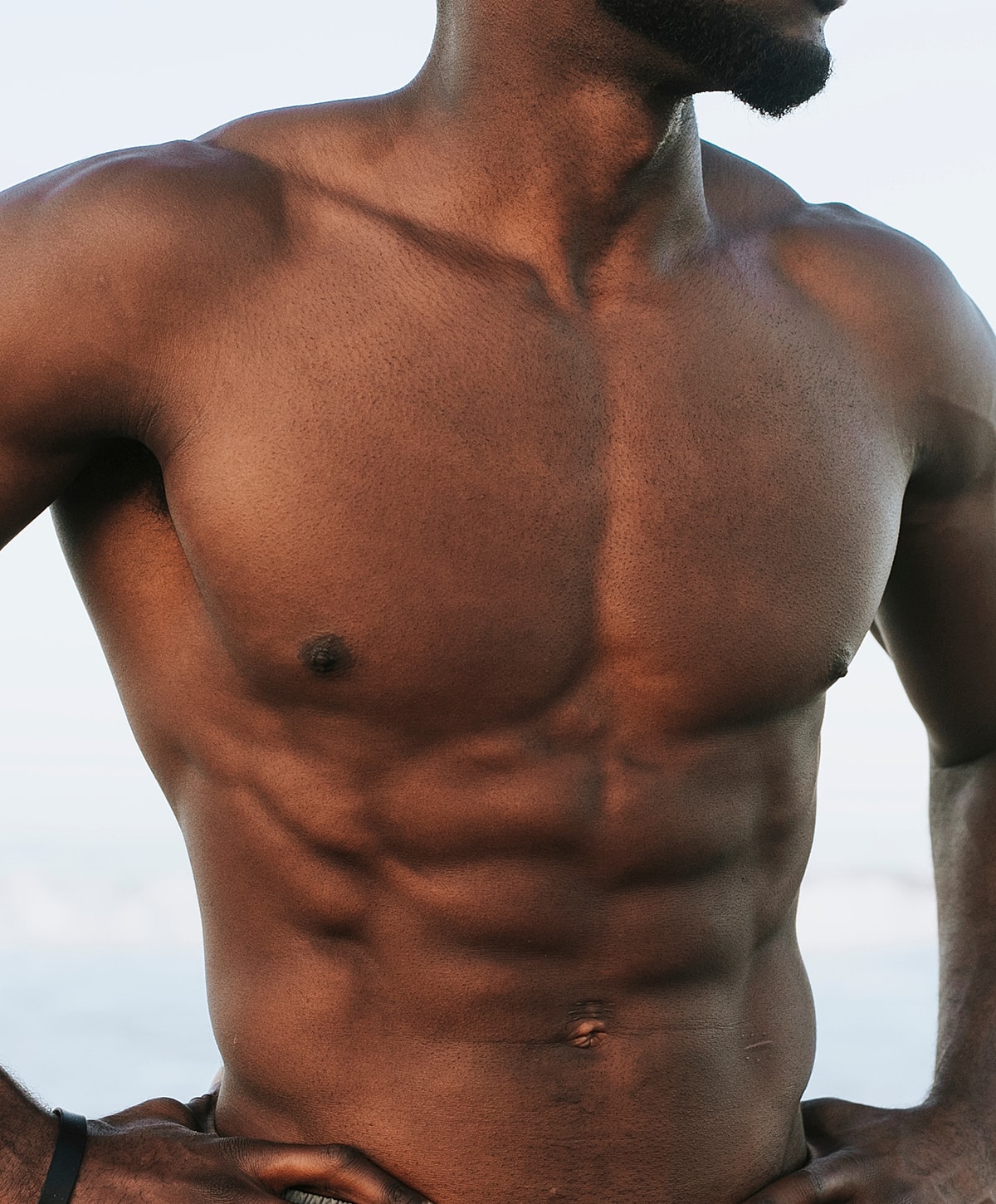 Close-up of fit male torso by the beach.