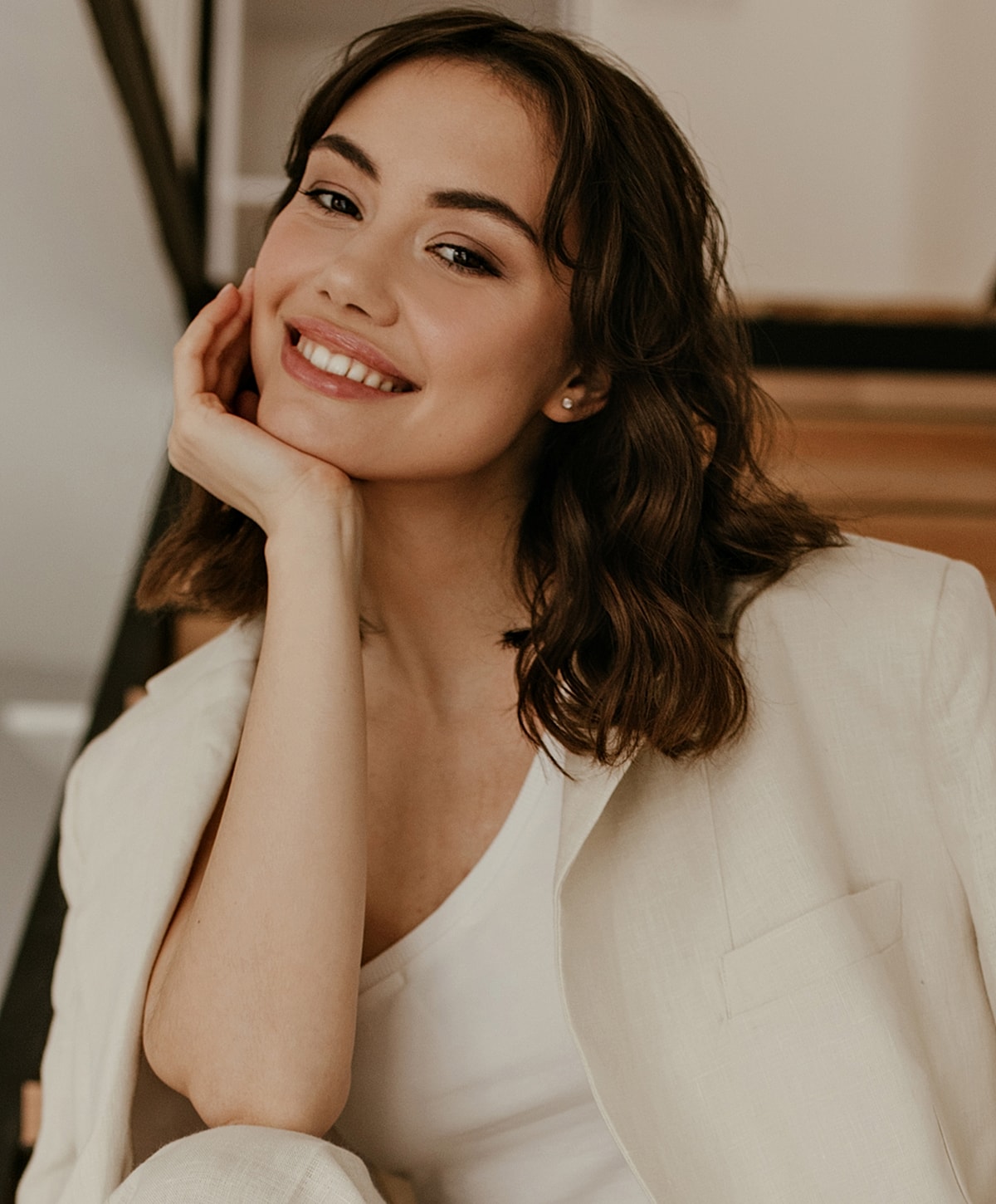 Smiling woman resting chin on hand, casual attire.