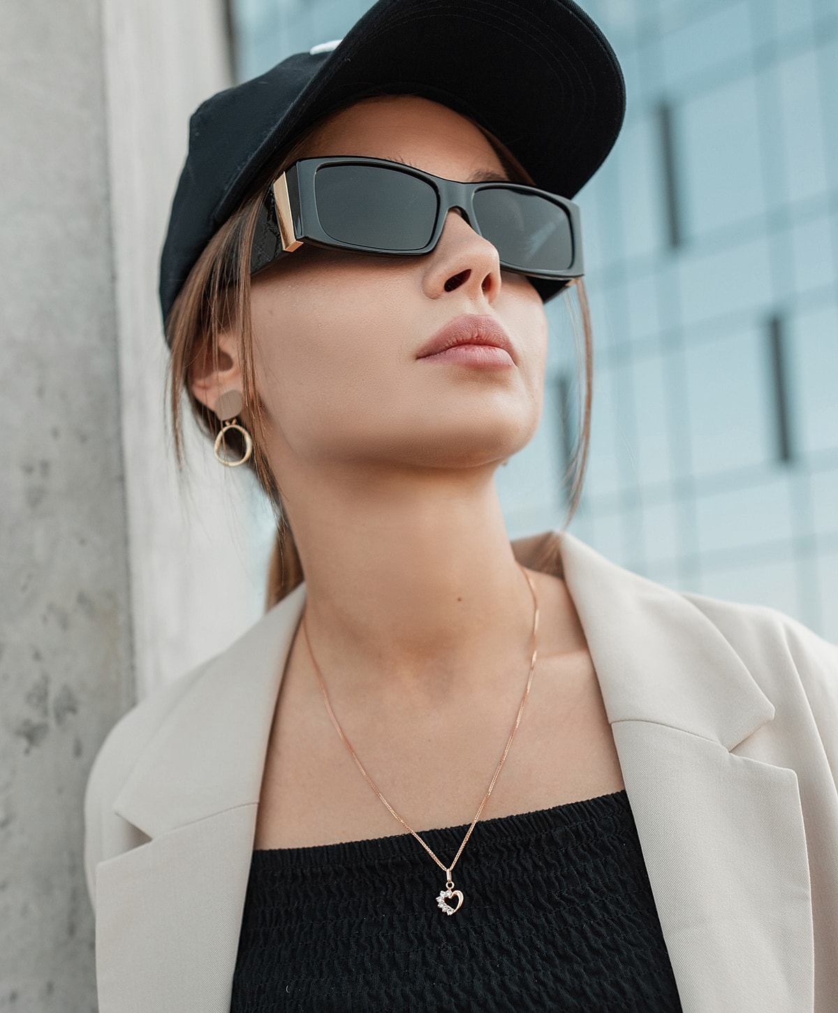 Woman in sunglasses and cap, stylish outfit.