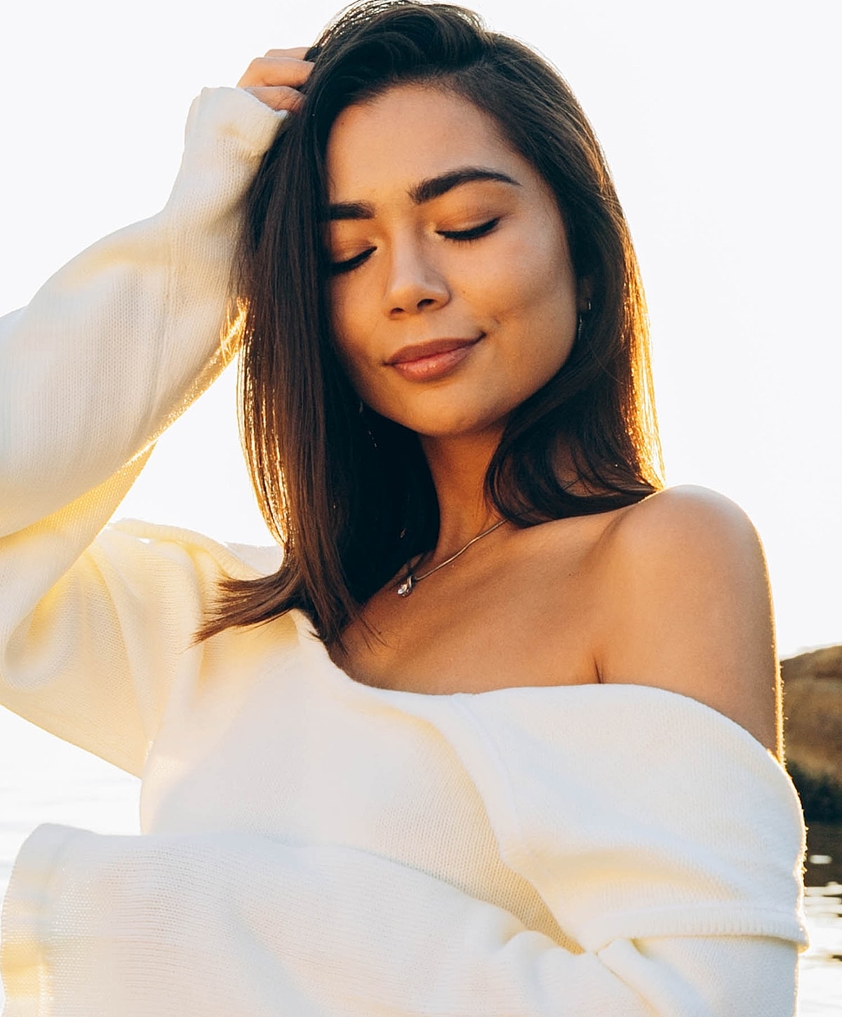 Woman with closed eyes, smiling by the water.