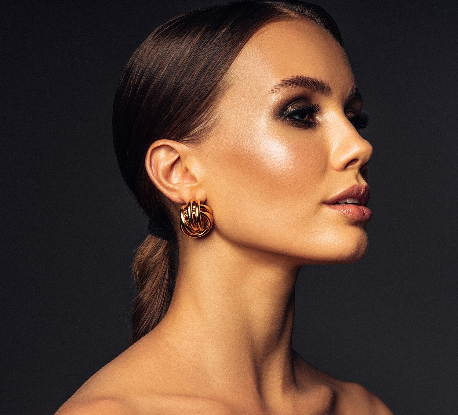 Profile of a woman with elegant gold earrings.