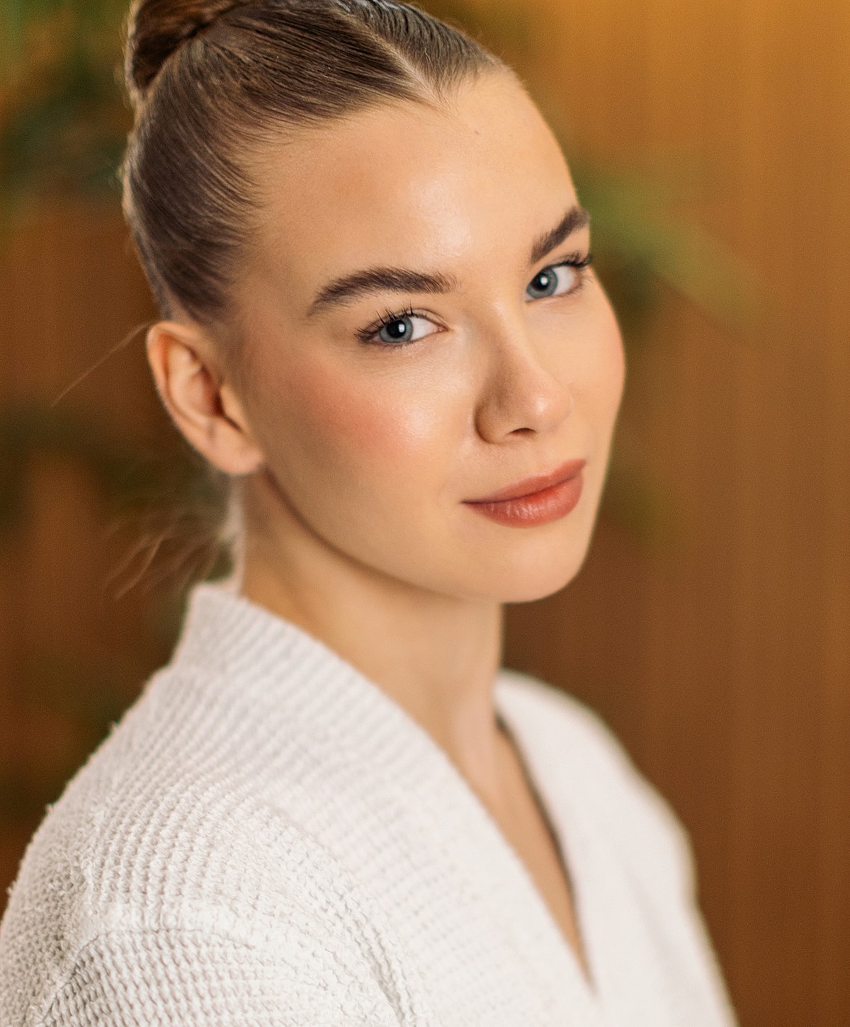 Woman in a white robe, softly smiling.