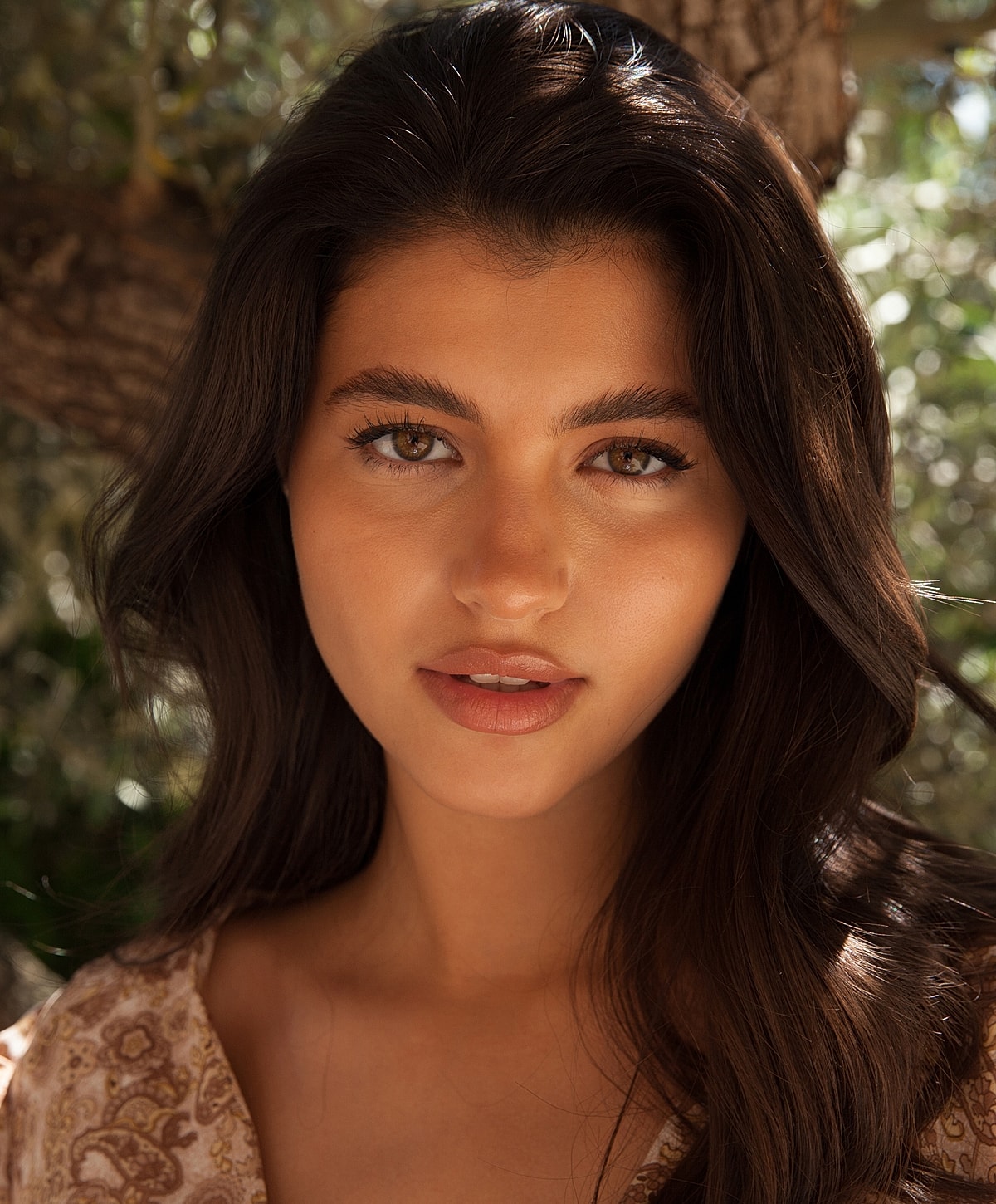 Young woman with long dark hair outdoors.