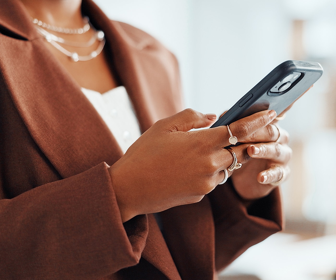 Person using smartphone with elegant jewelry on hands.