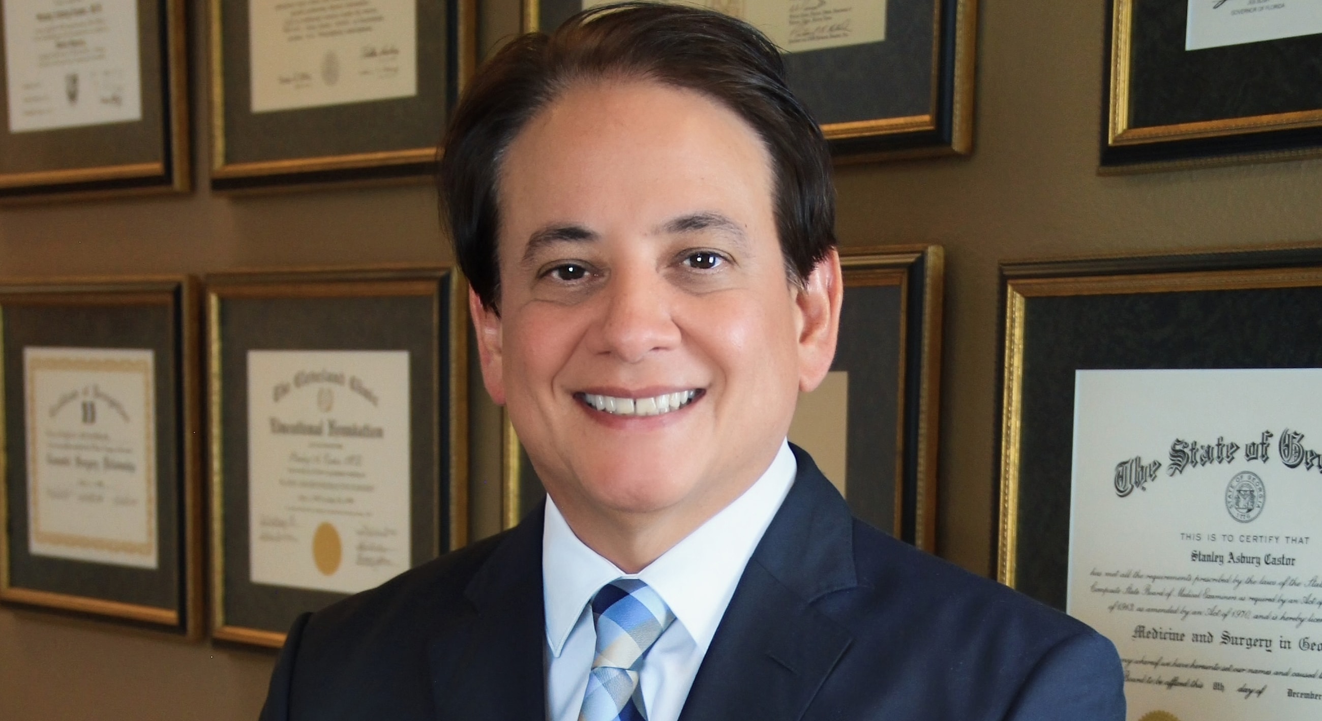 Professional portrait with diplomas in background.