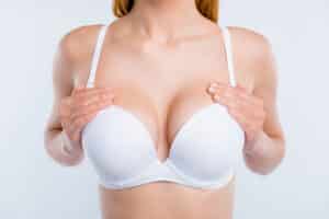 A cropped shot of a woman in a white bra after a breast augmentation