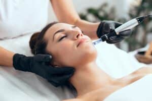 Woman getting professional microneedling treatment done at spa.